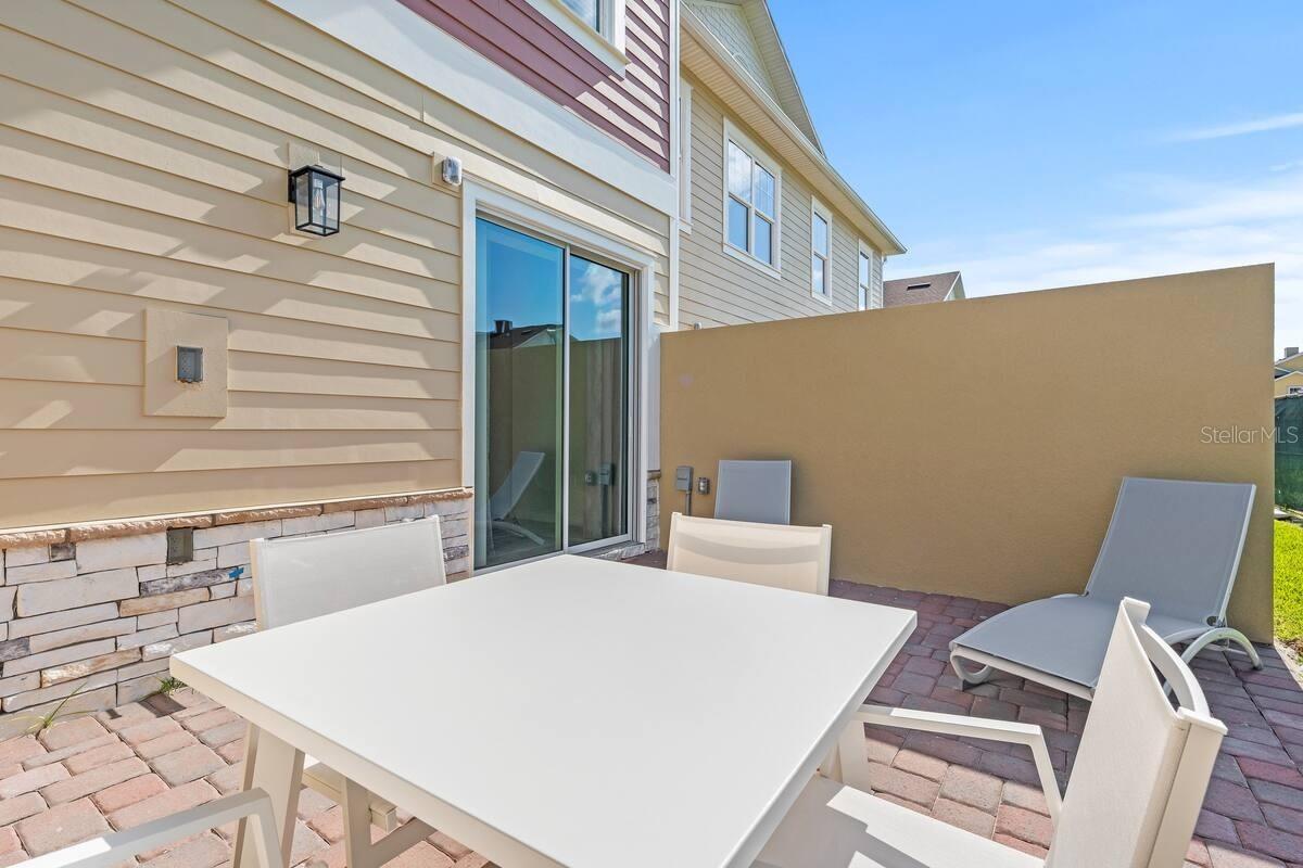 Enclosed patio with a white dining set, gray lounge chairs, and a sliding glass door.