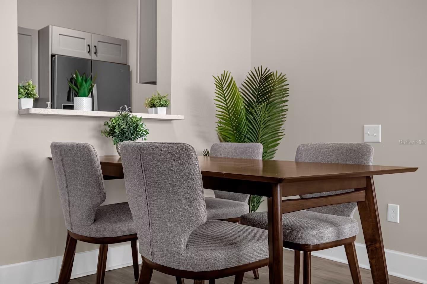 Dining area with a dark wood table, gray upholstered chairs, and a pass-through to the kitchen.