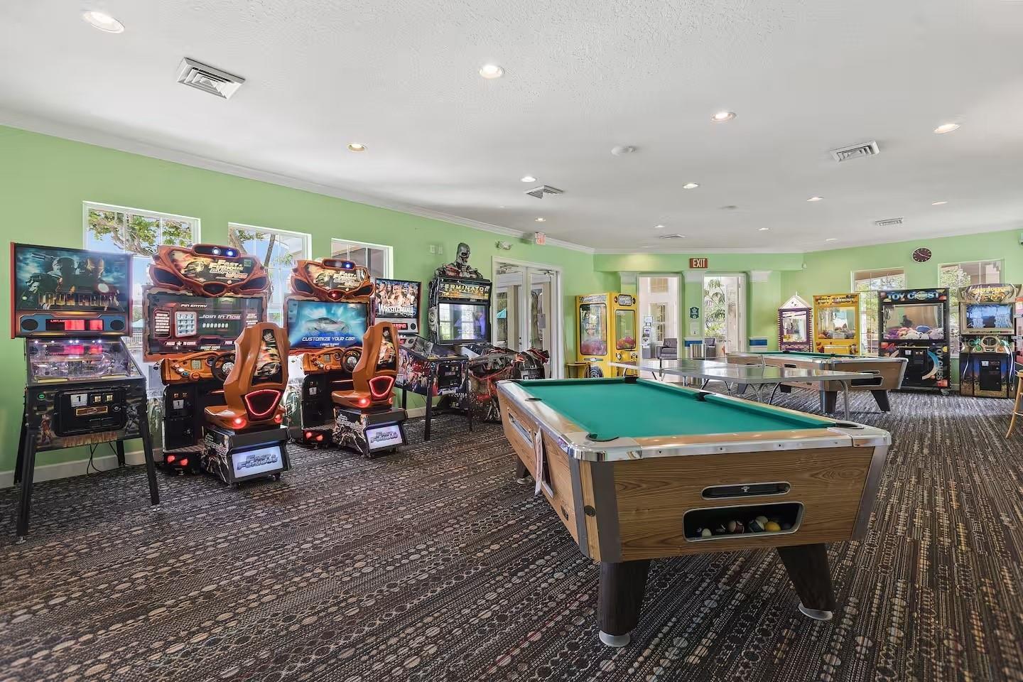 Game room with a green pool table and rows of arcade machines.