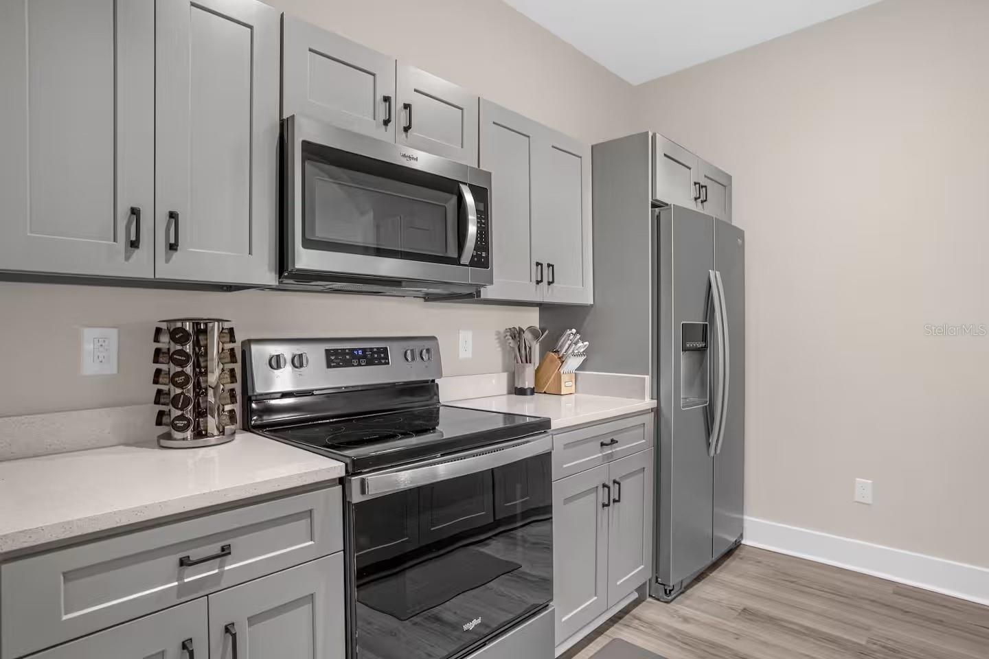 Modern kitchen with gray cabinets, white countertops, and stainless-steel appliances.