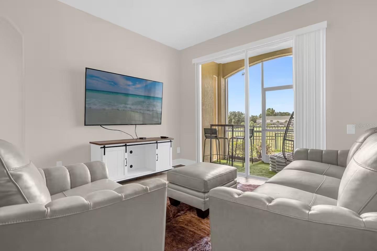 Living room with gray sectional sofas and sliding doors opening onto a patio.