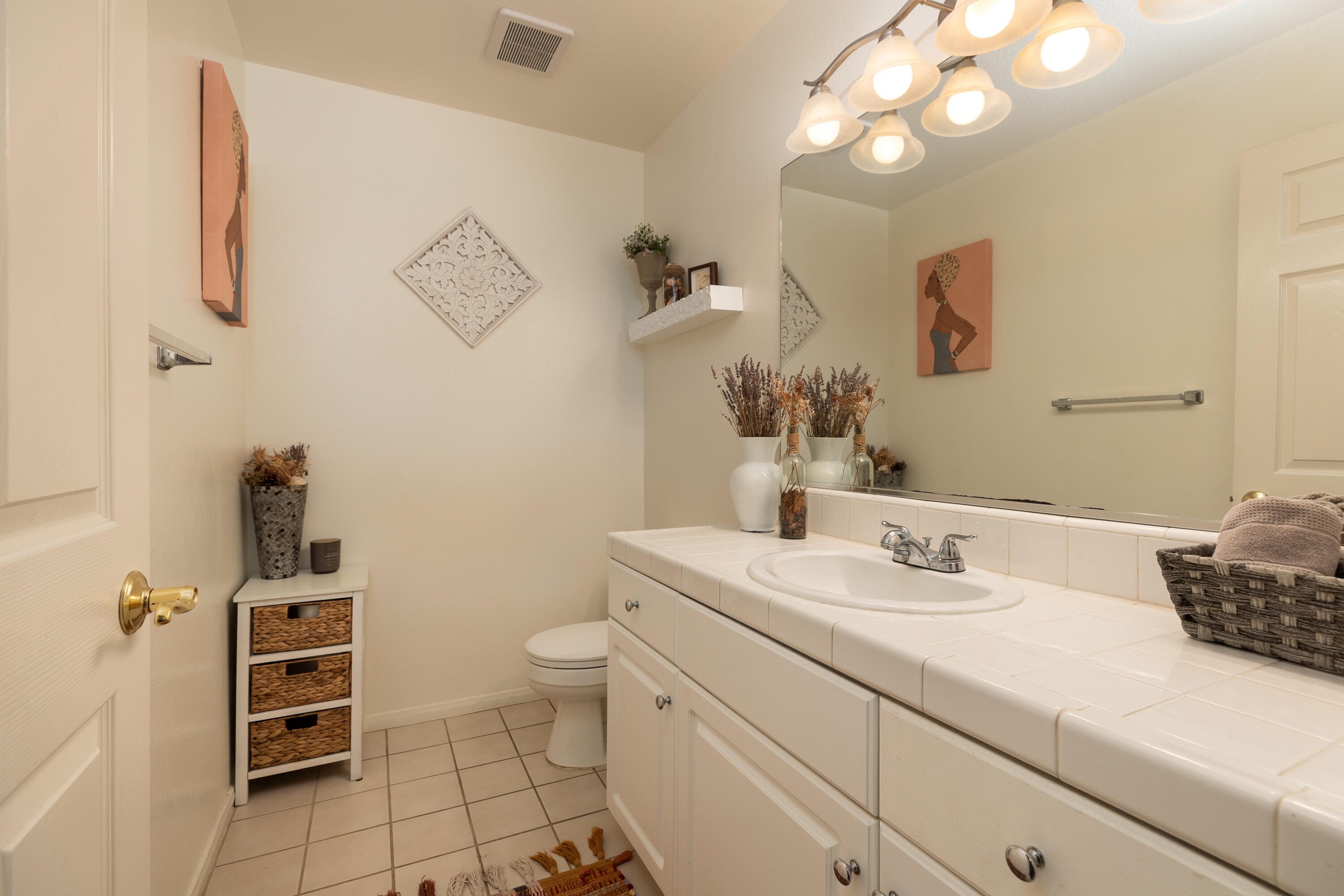 Bathroom with a long white tiled vanity, large mirror, and decorative artwork.