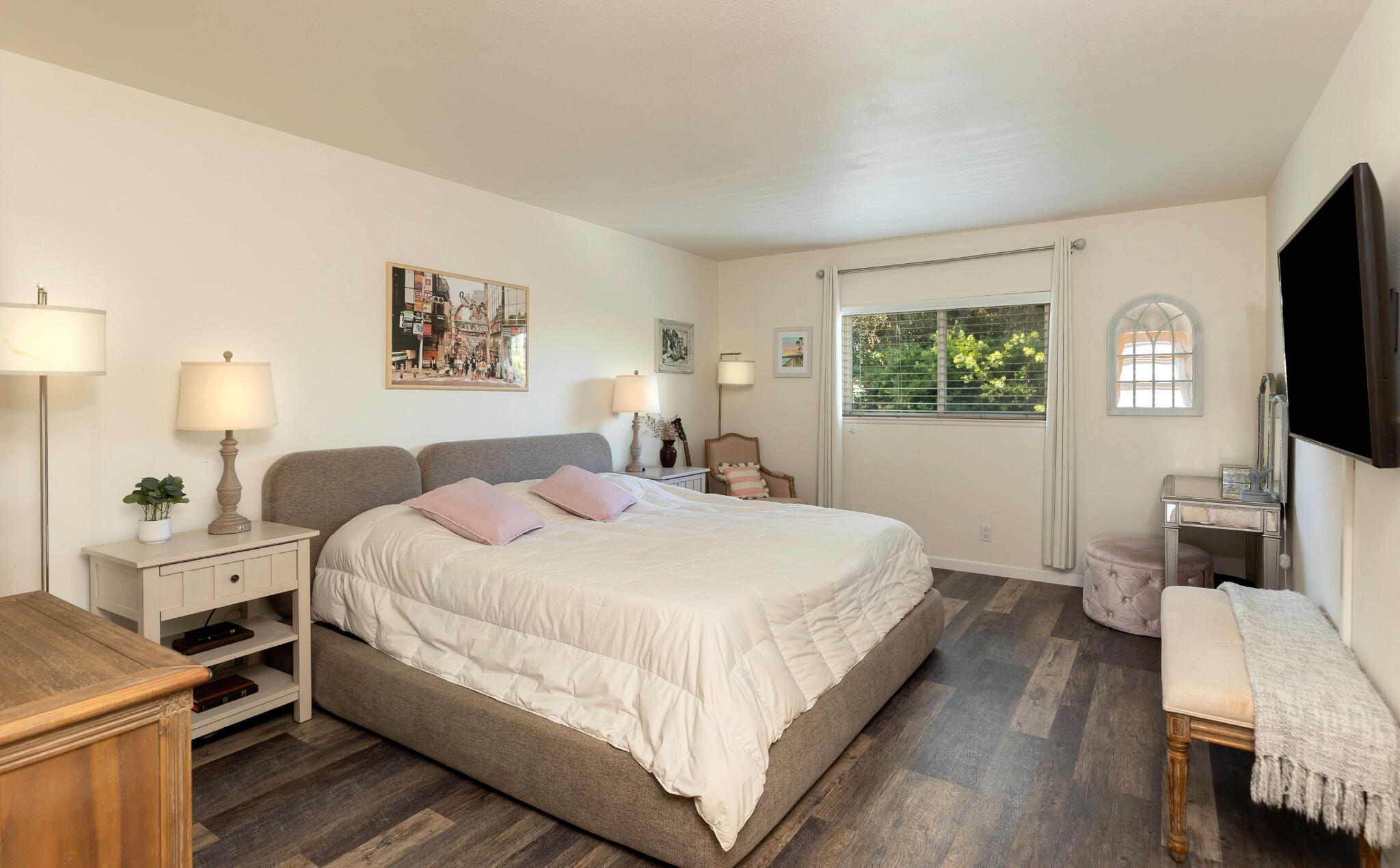 Bedroom with a large bed, pink accent pillows, and a window overlooking greenery.