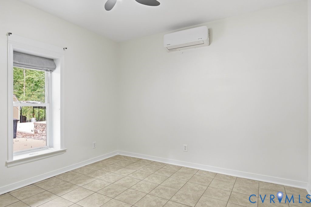 Empty tiled room with a window and wall-mounted mini-split air conditioner.
