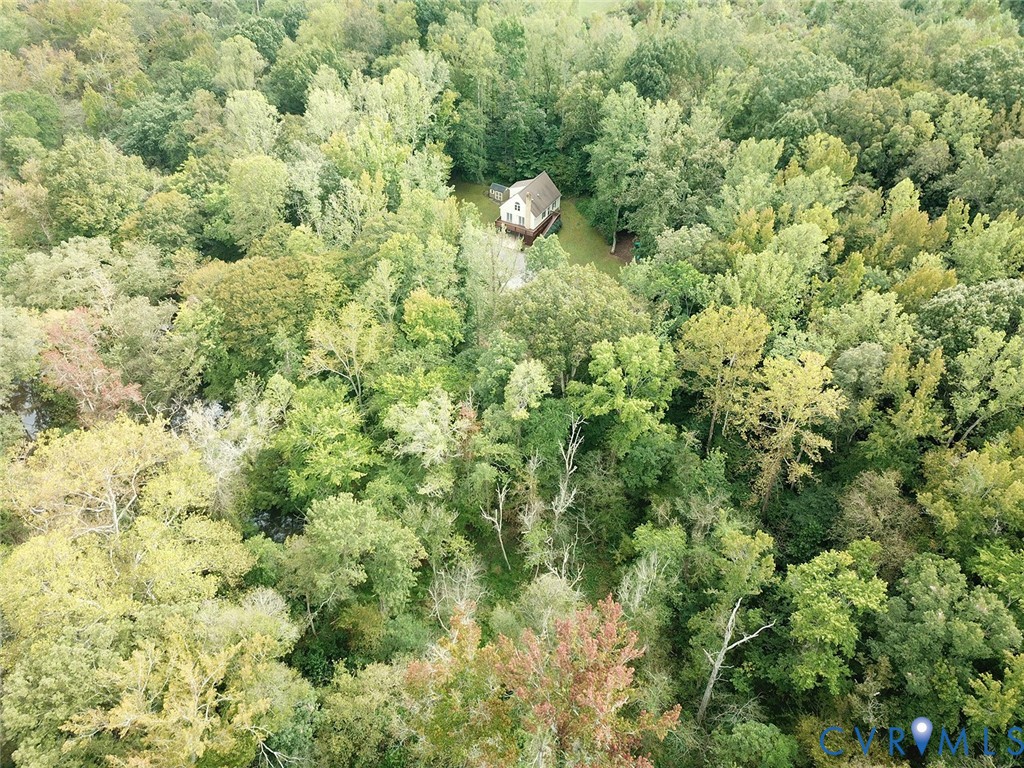 Aerial view of a house in a clearing surrounded by dense woodland.