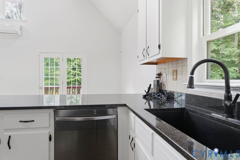 Kitchen with black countertops and sink, white cabinets, and a stainless steel dishwasher.