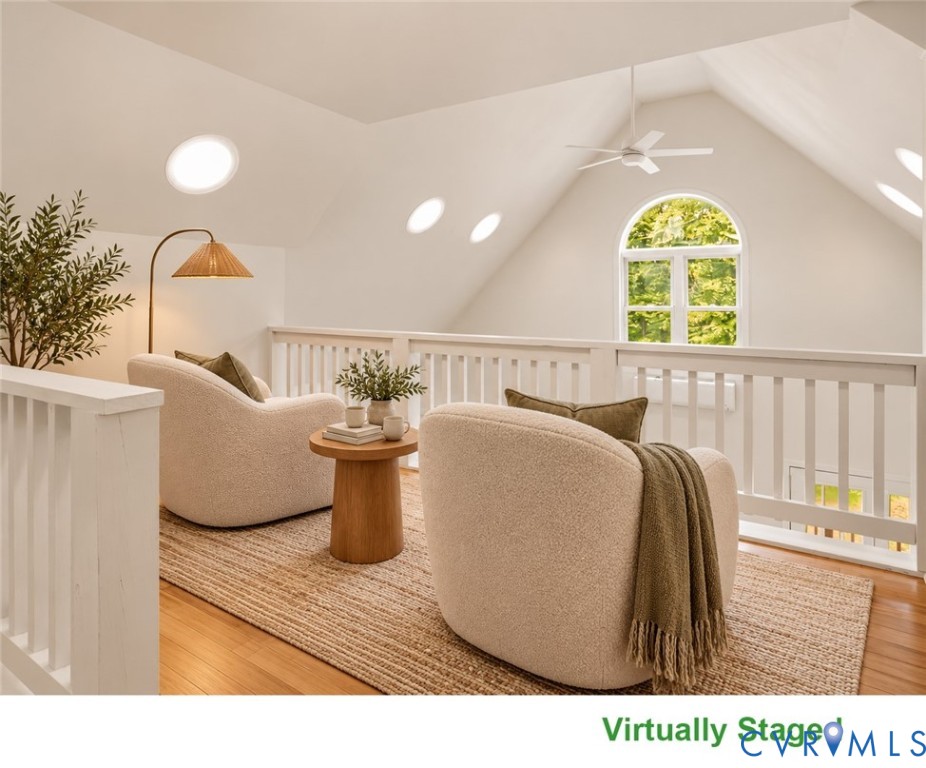 Loft sitting area with vaulted ceiling, arched window, and two chairs around a small table.