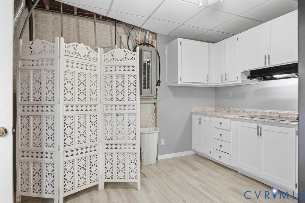 White kitchenette with speckled countertops beside a folding screen concealing a utility area.