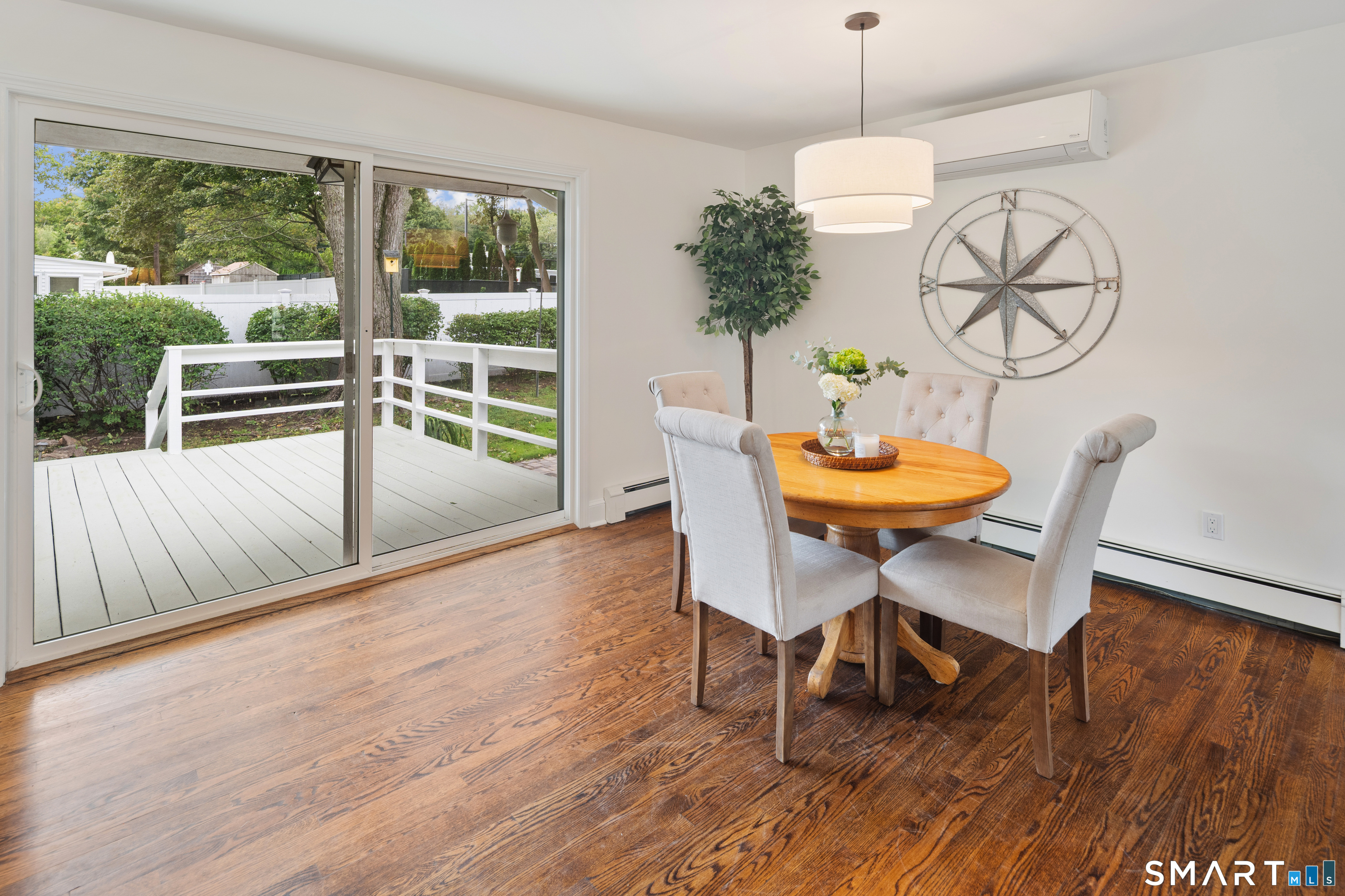 Dining area with a round wooden table beside sliding glass doors to a white deck.