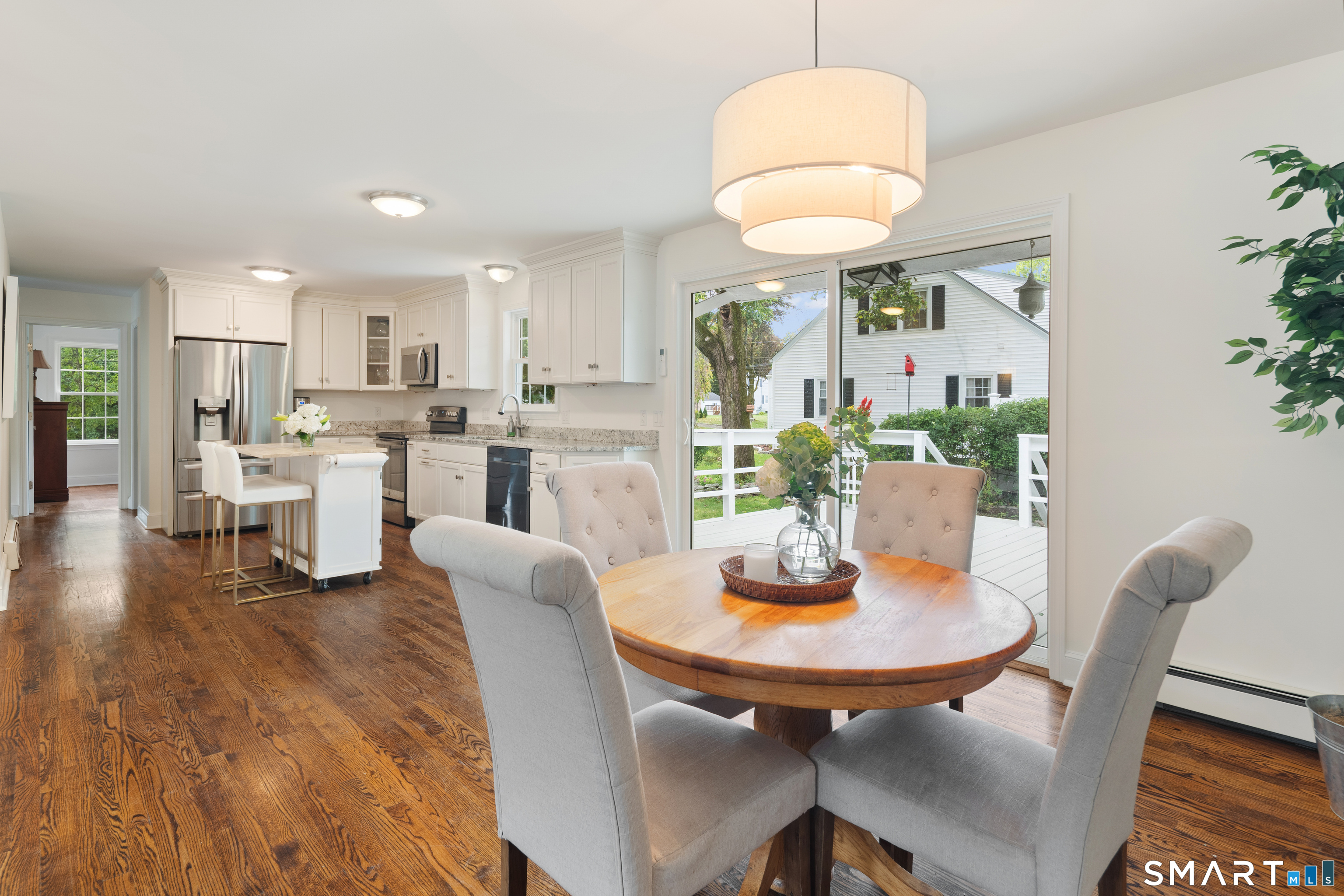 Open kitchen and dining area with white cabinetry, dark wood floors, and sliding doors to a deck.