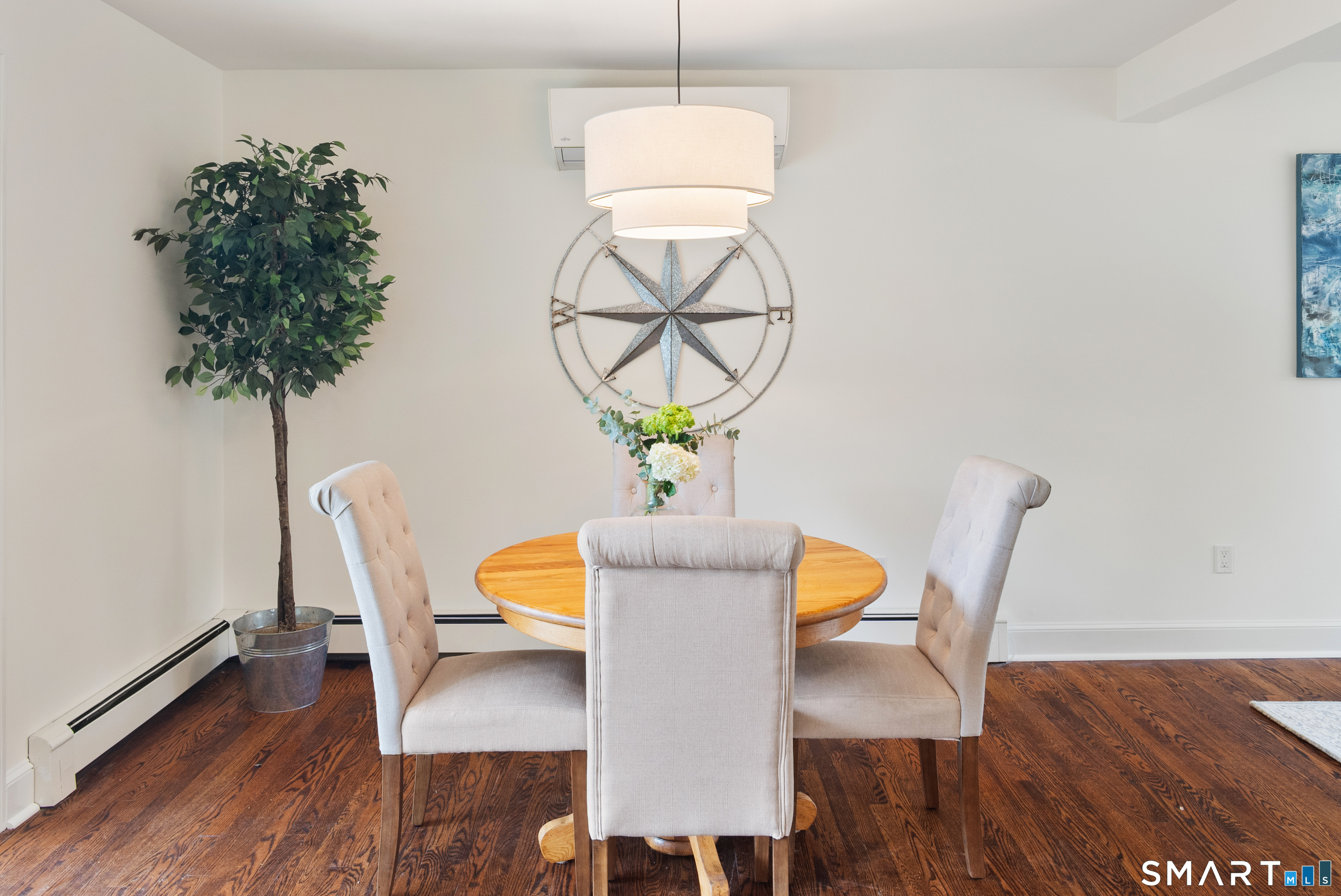 Dining room with a round wood table, upholstered chairs, and dark hardwood floors.