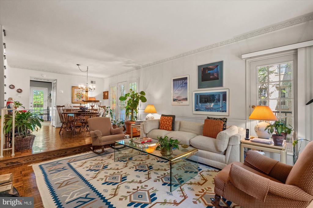 Living room with a cream sofa, patterned rug, glass coffee table, and adjoining dining area.