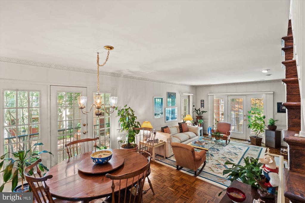 Furnished living and dining room with parquet floors, French doors, and a wooden staircase.