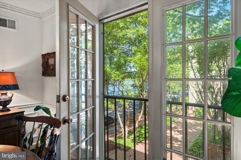 Interior with tall French doors overlooking a leafy courtyard and brick paving.