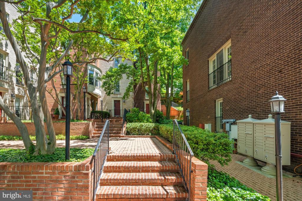 Brick steps lead through a leafy courtyard between residential buildings.