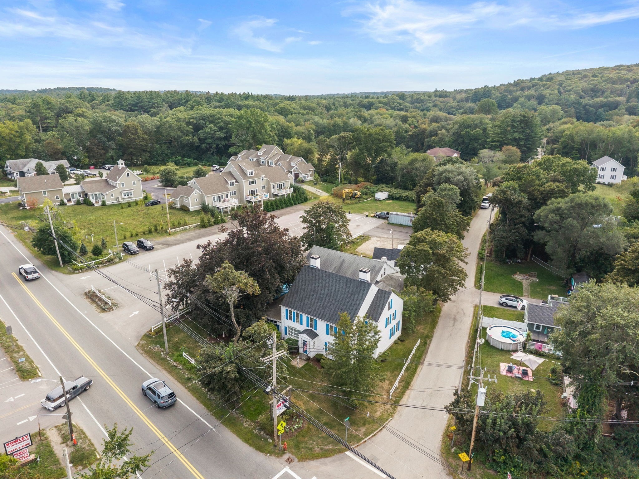 Aerial view of a white house with blue shutters on a corner lot beside a road intersection.