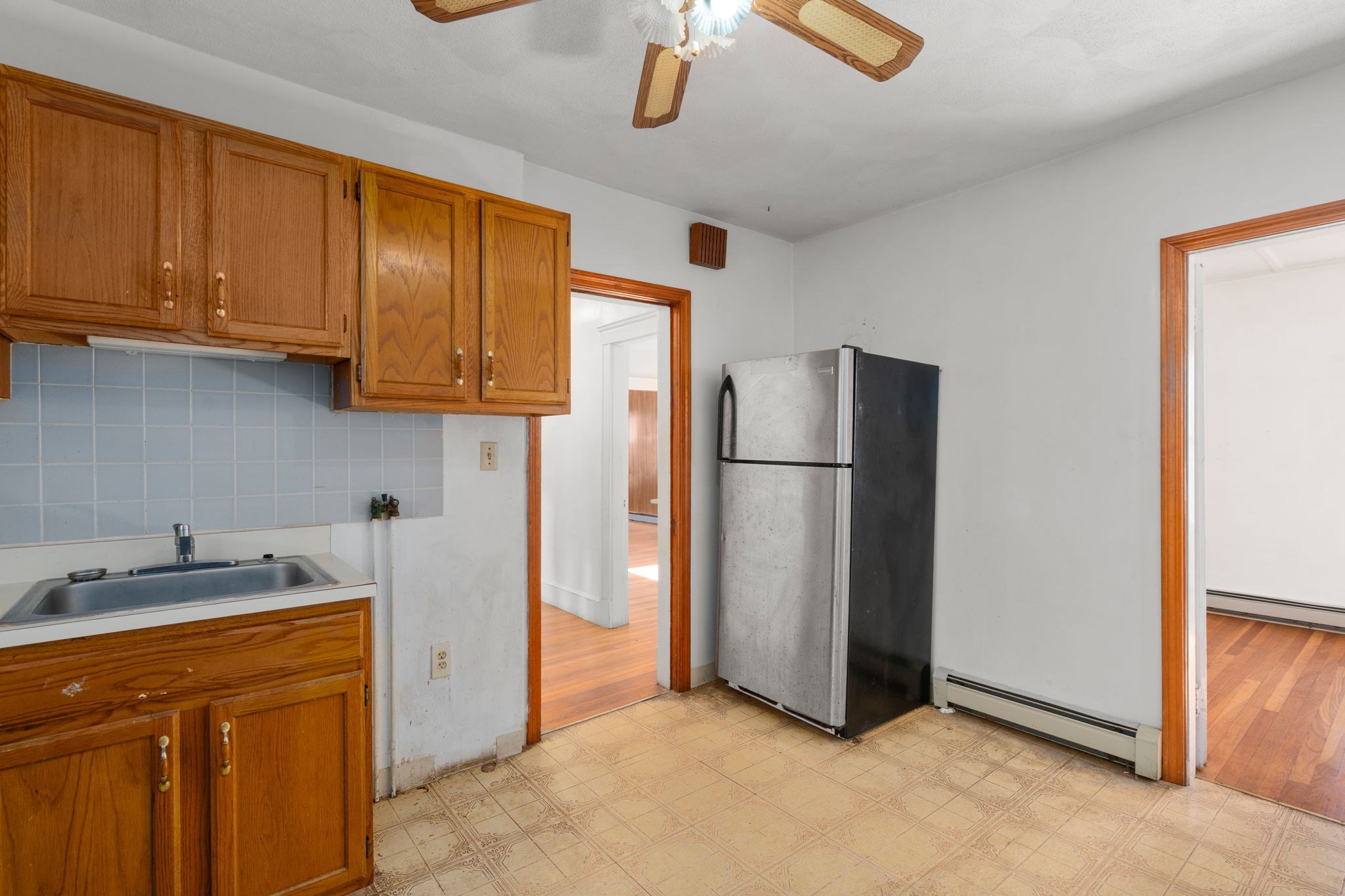 Kitchen with wood cabinets, blue tile backsplash, and a top-freezer refrigerator
