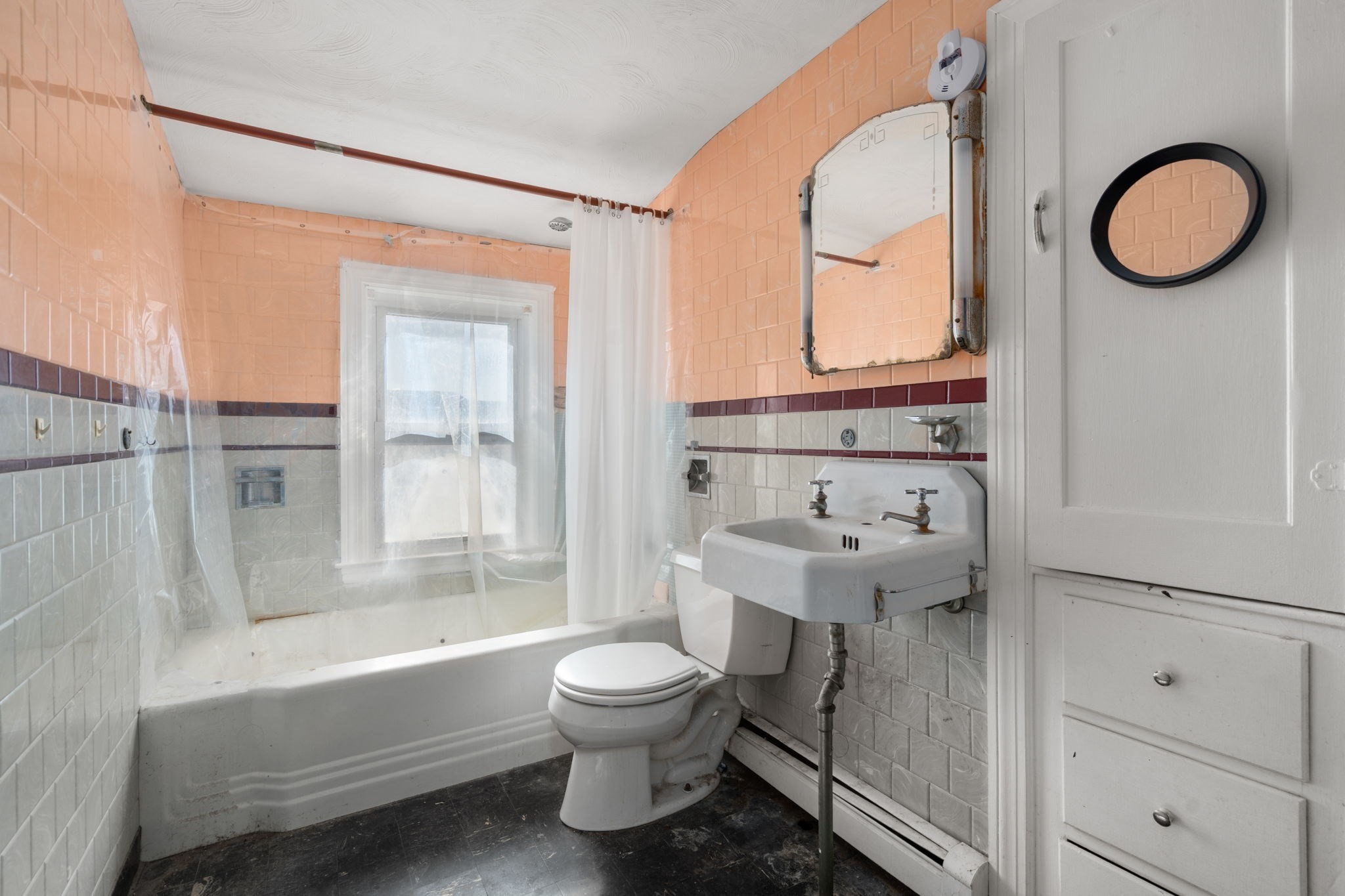Bathroom with peach-pink tile, a curtained bathtub, toilet, and wall-mounted sink.