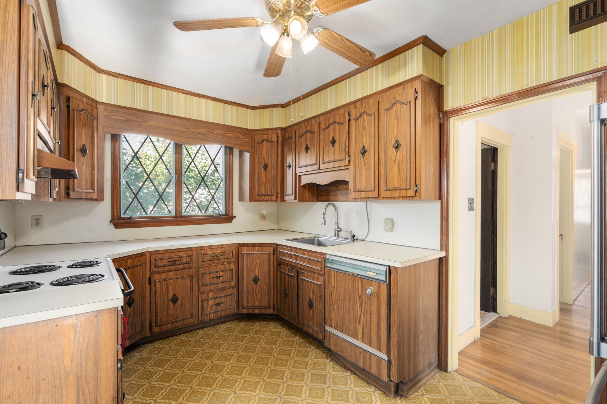 Kitchen with dark wood cabinets, a diamond-pane window, and patterned flooring.