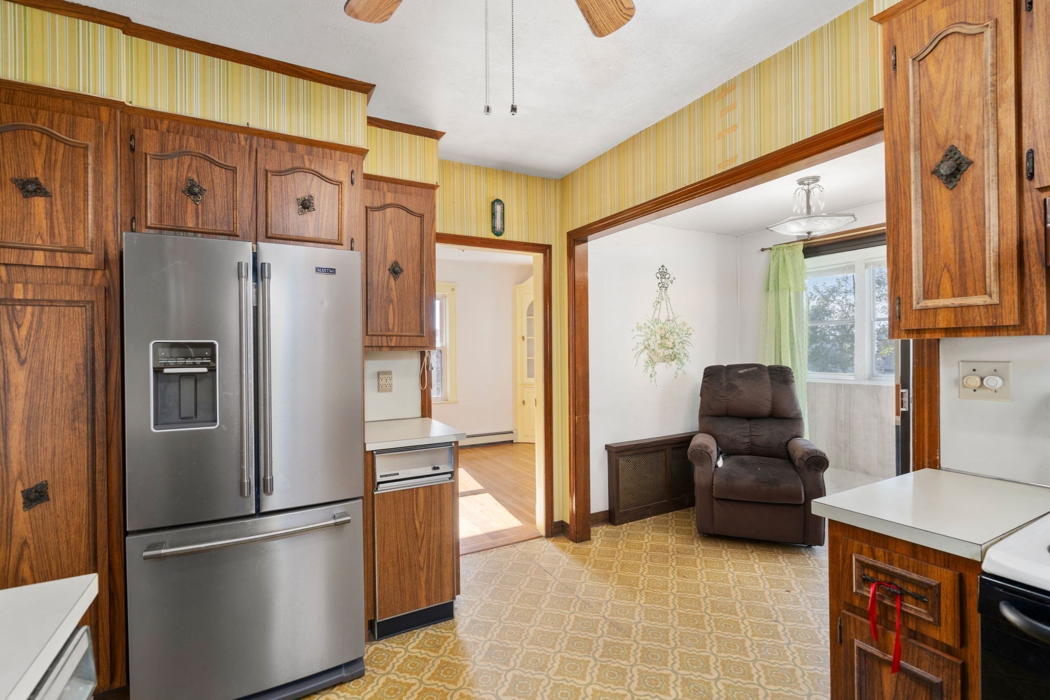 Kitchen with dark wood cabinetry, stainless refrigerator, patterned flooring, and an adjoining seating nook.