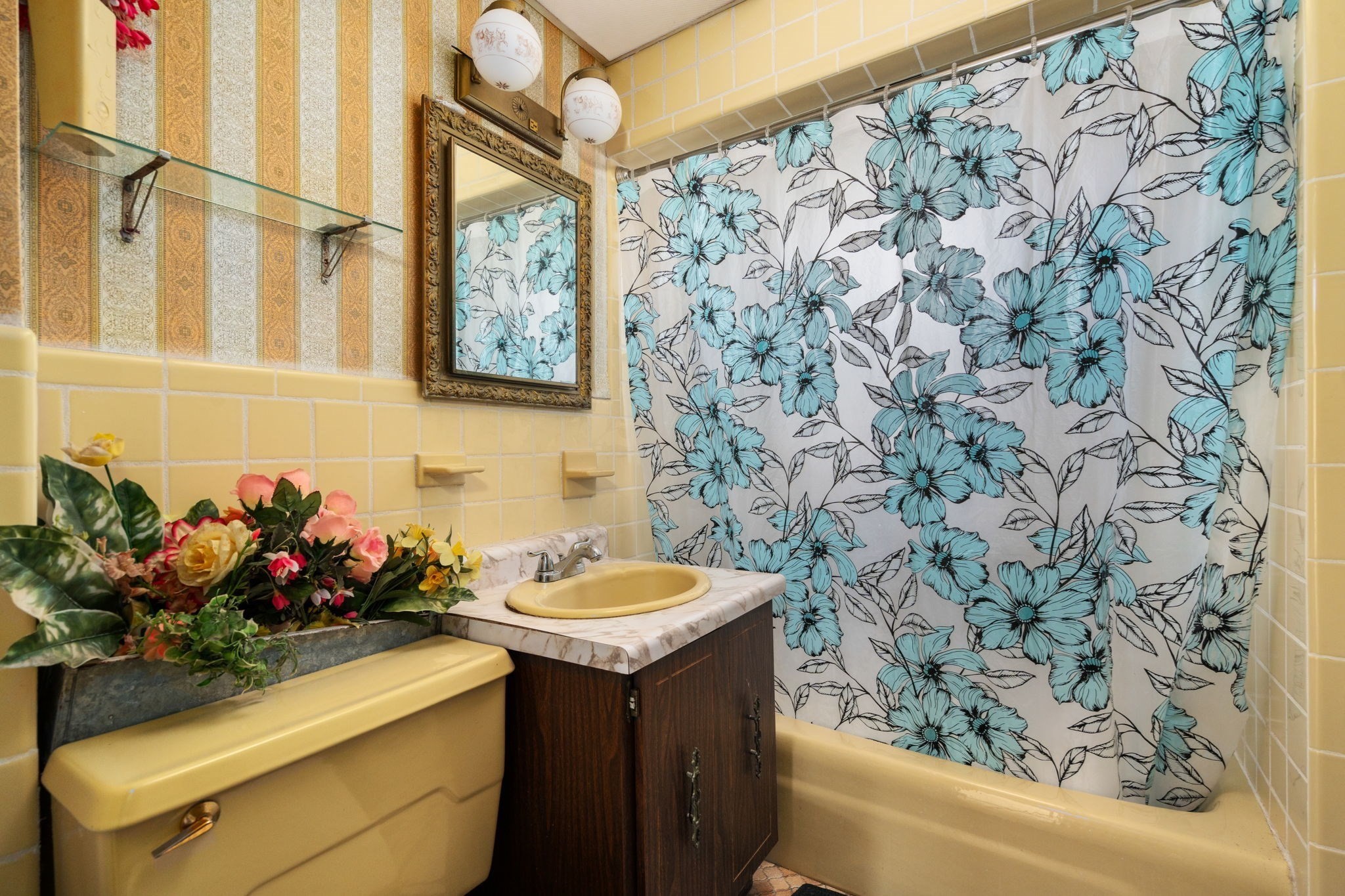 Bathroom with yellow fixtures, a dark wood vanity, and a blue floral shower curtain.