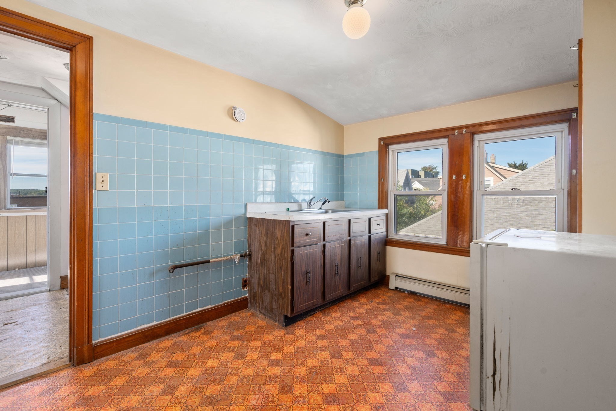 Kitchen with blue tile walls, dark wood sink cabinets, and patterned orange flooring.