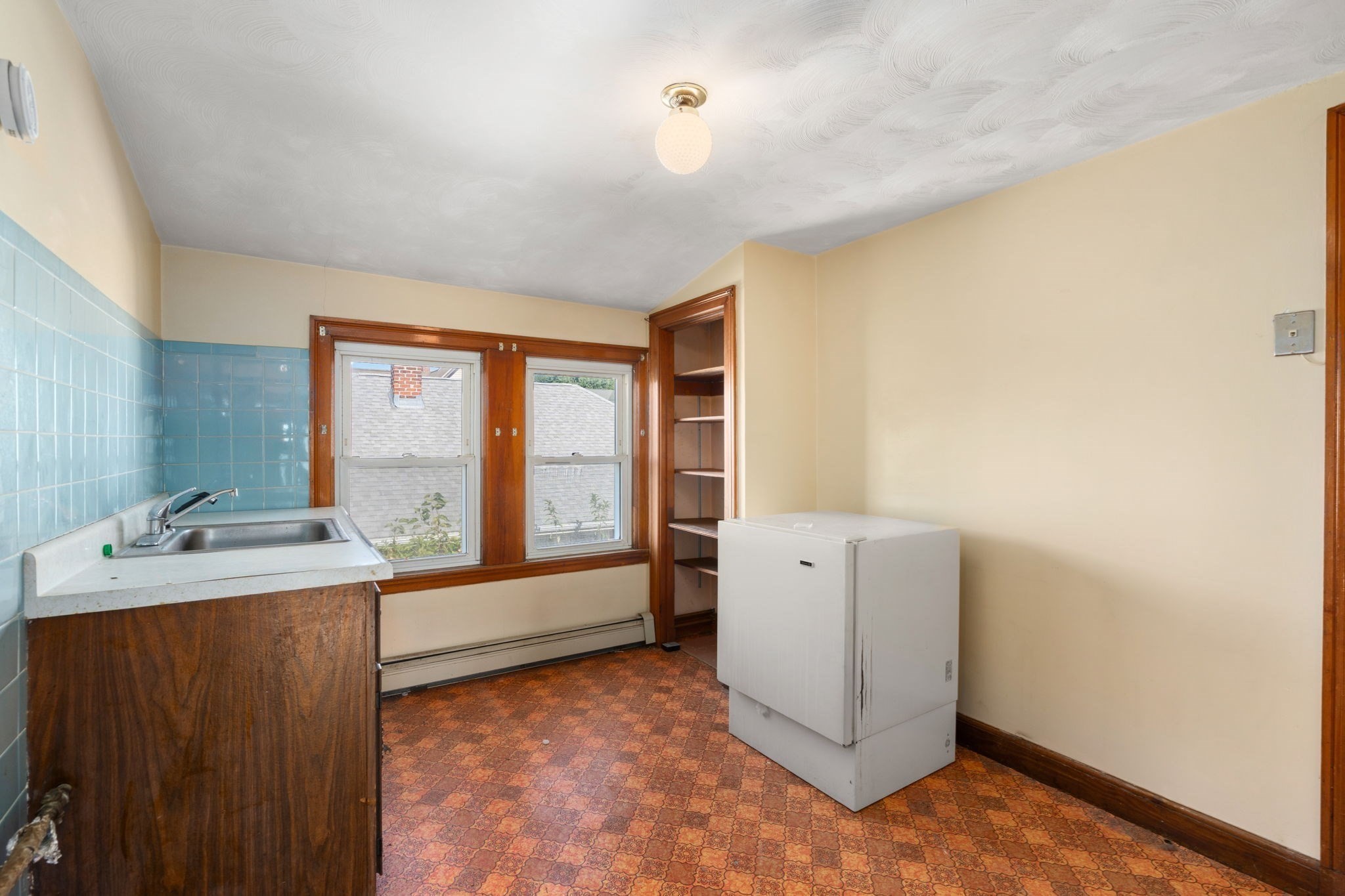 Kitchen with blue tile, a wood-cabinet sink, built-in shelving, and a white chest freezer.