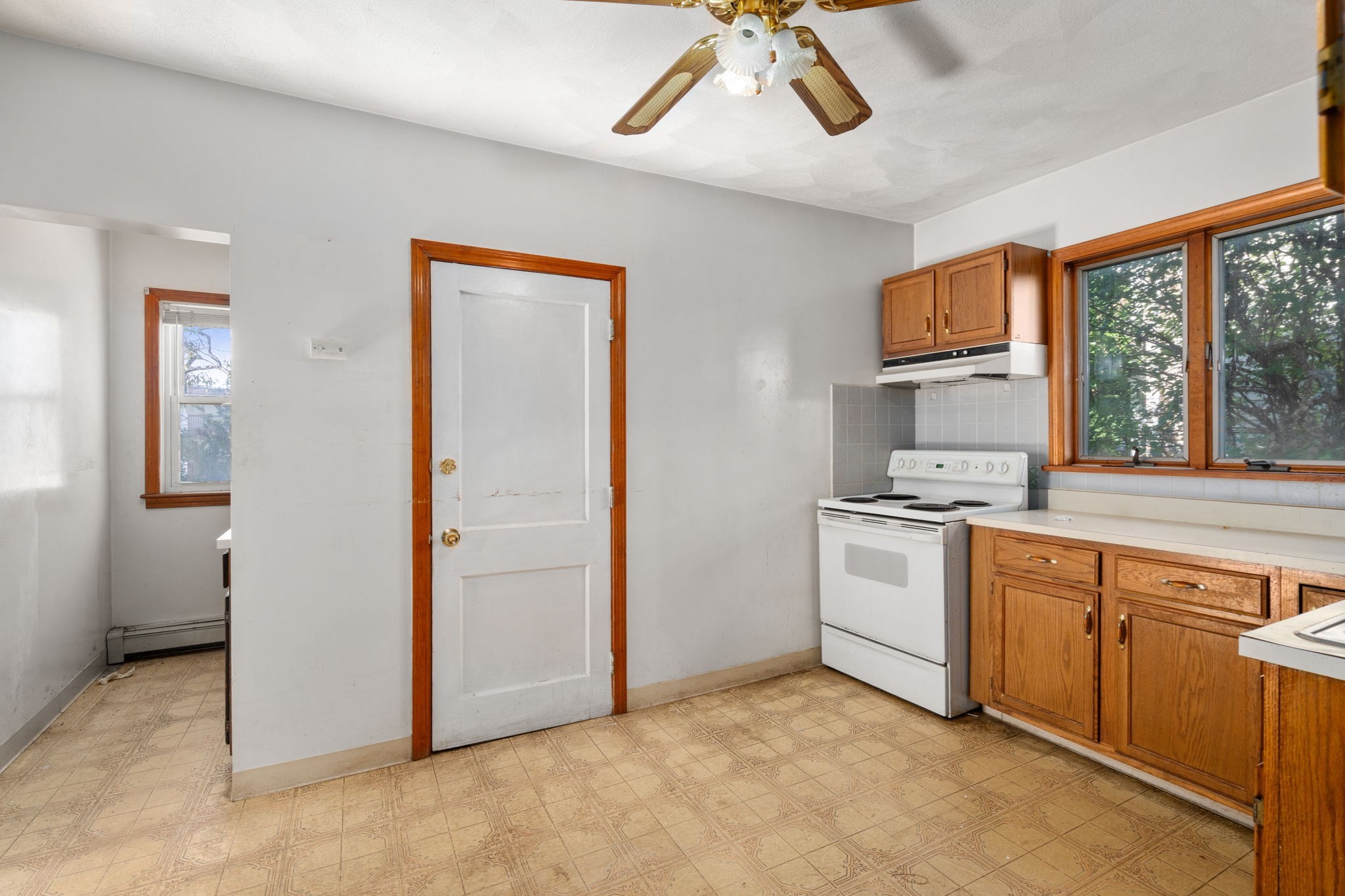 Kitchen with wood cabinets, a white electric range, and large wood-trimmed windows.