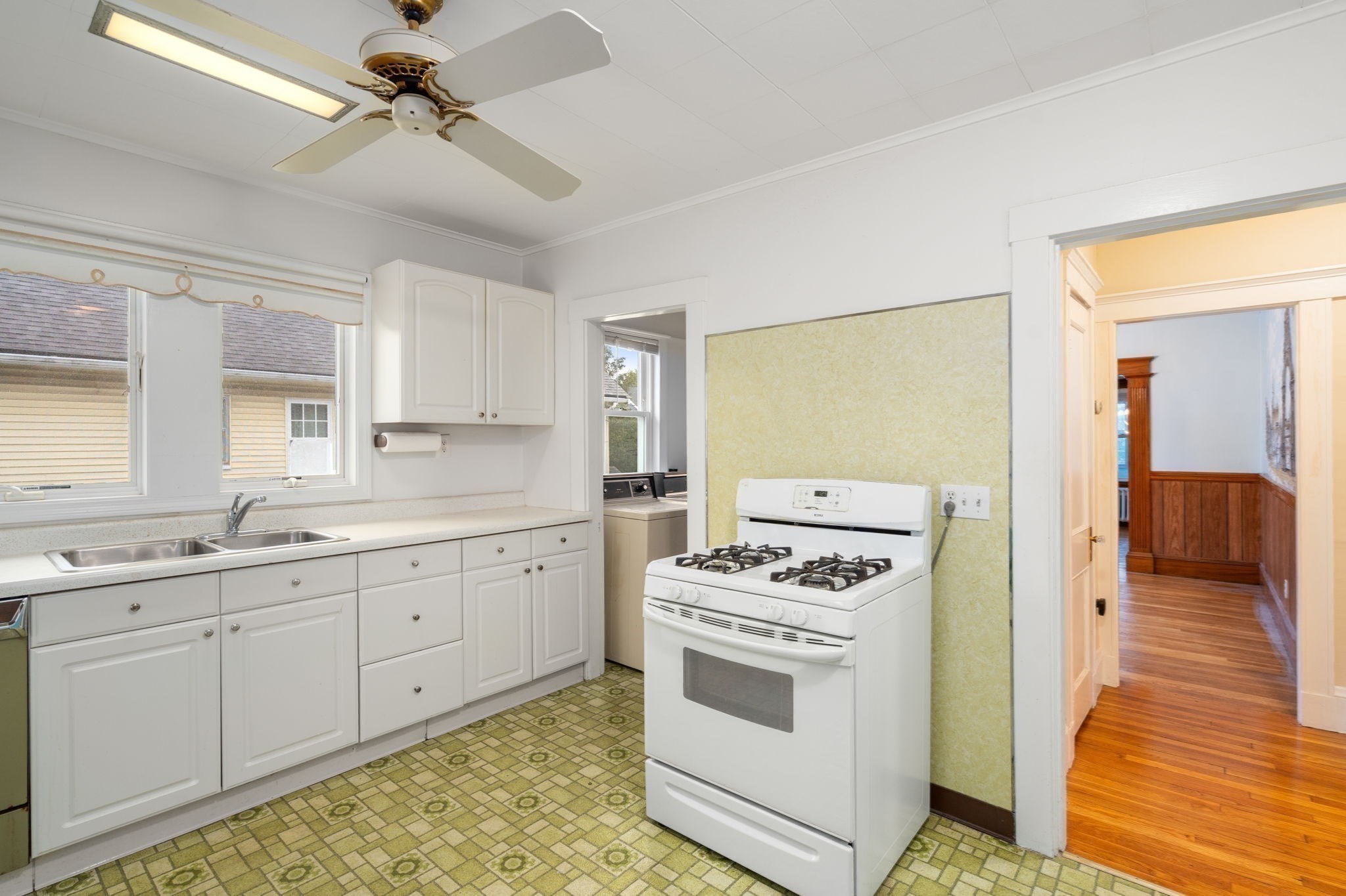 Kitchen with white cabinets, a gas range, double sink, and green patterned floor.