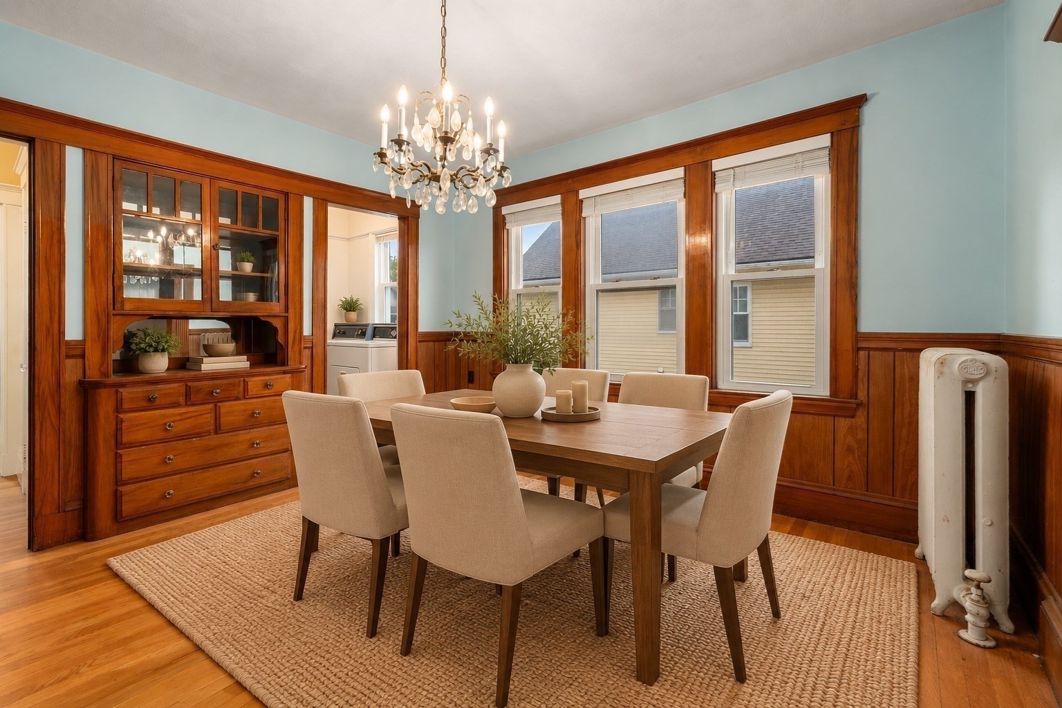 Dining room with wood built-ins, a chandelier, and a table beside three windows.