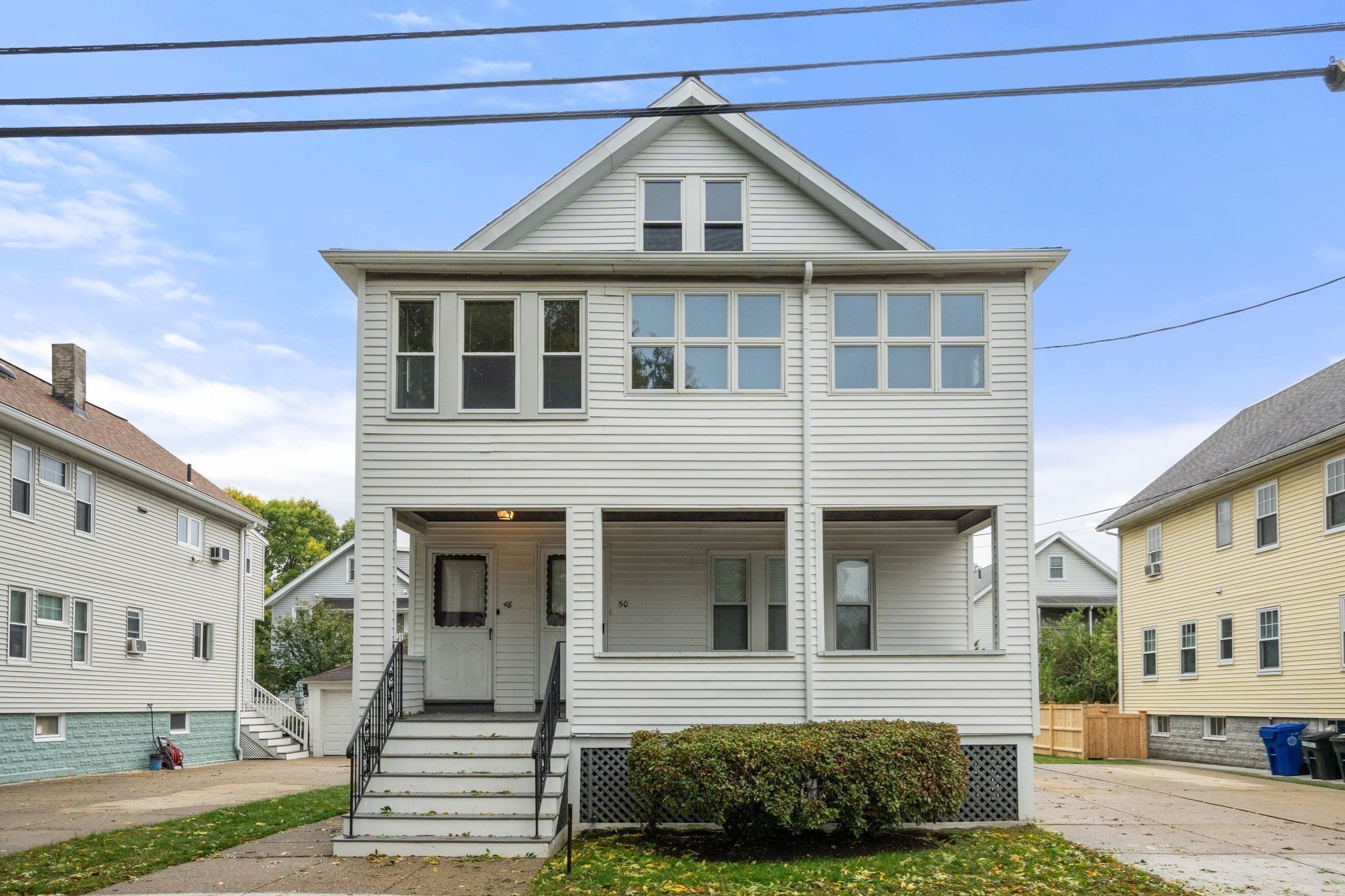 White two-unit house with separate 48 and 50 entrances, raised porch, and broad upper windows.