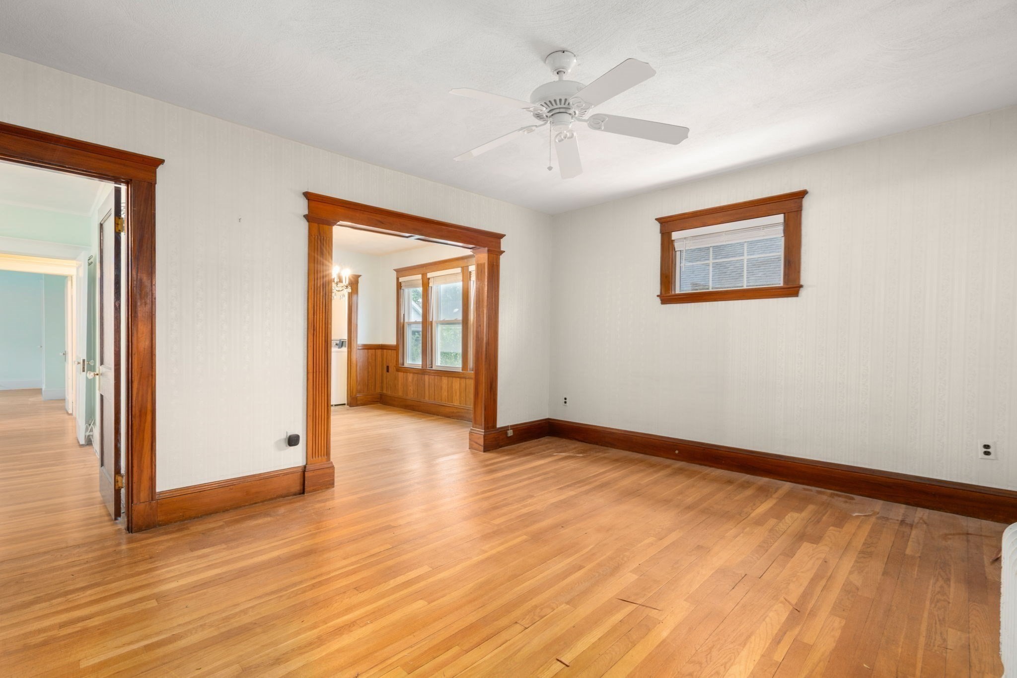 Empty room with hardwood floors, dark wood trim, and a ceiling fan.