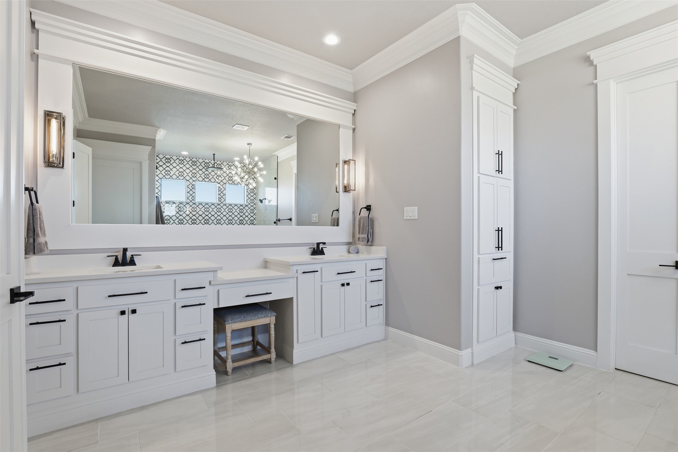 Bathroom with a white double vanity, large mirror, and tall built-in linen cabinets.