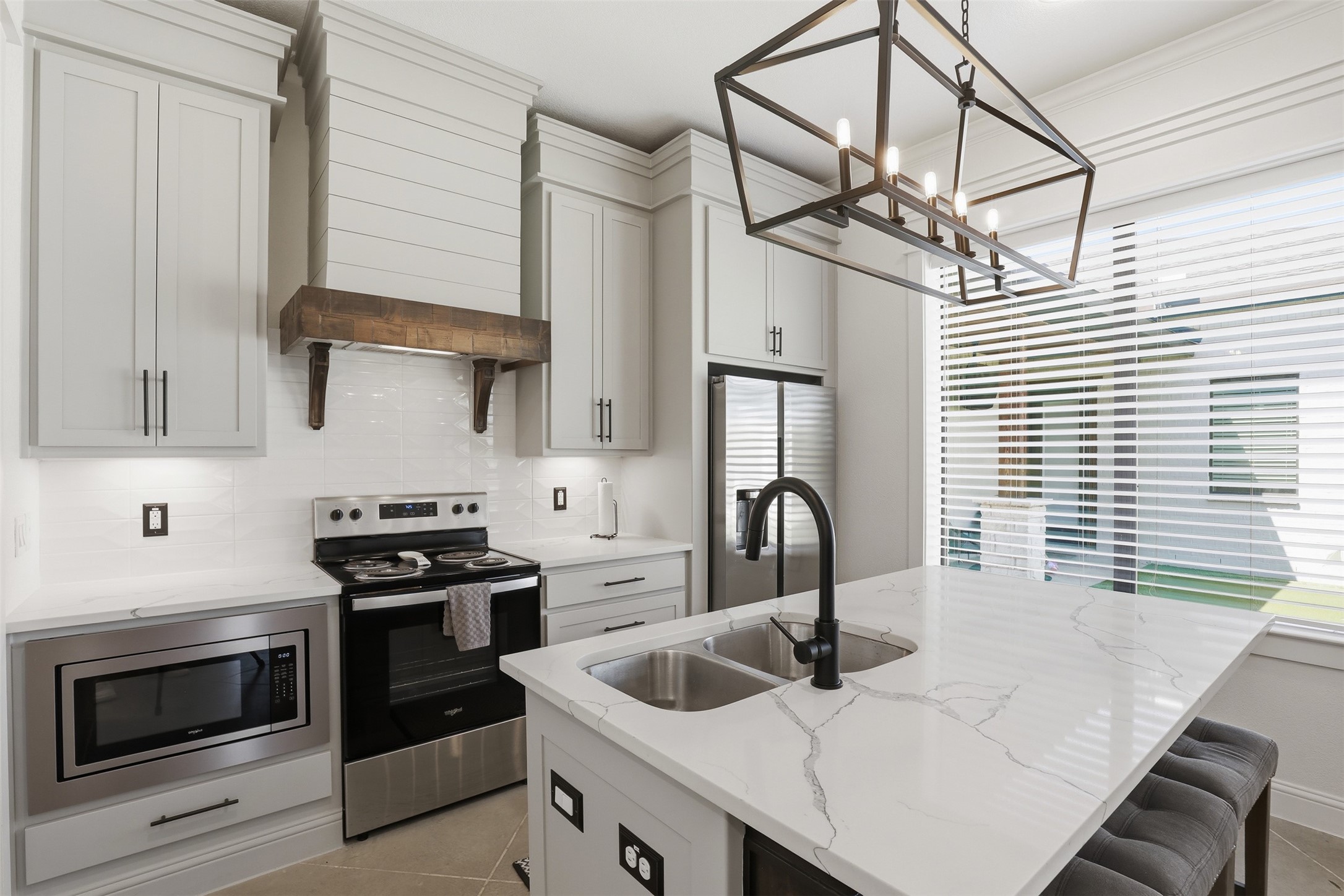 Modern kitchen with a veined stone island, double sink, and stainless steel appliances.