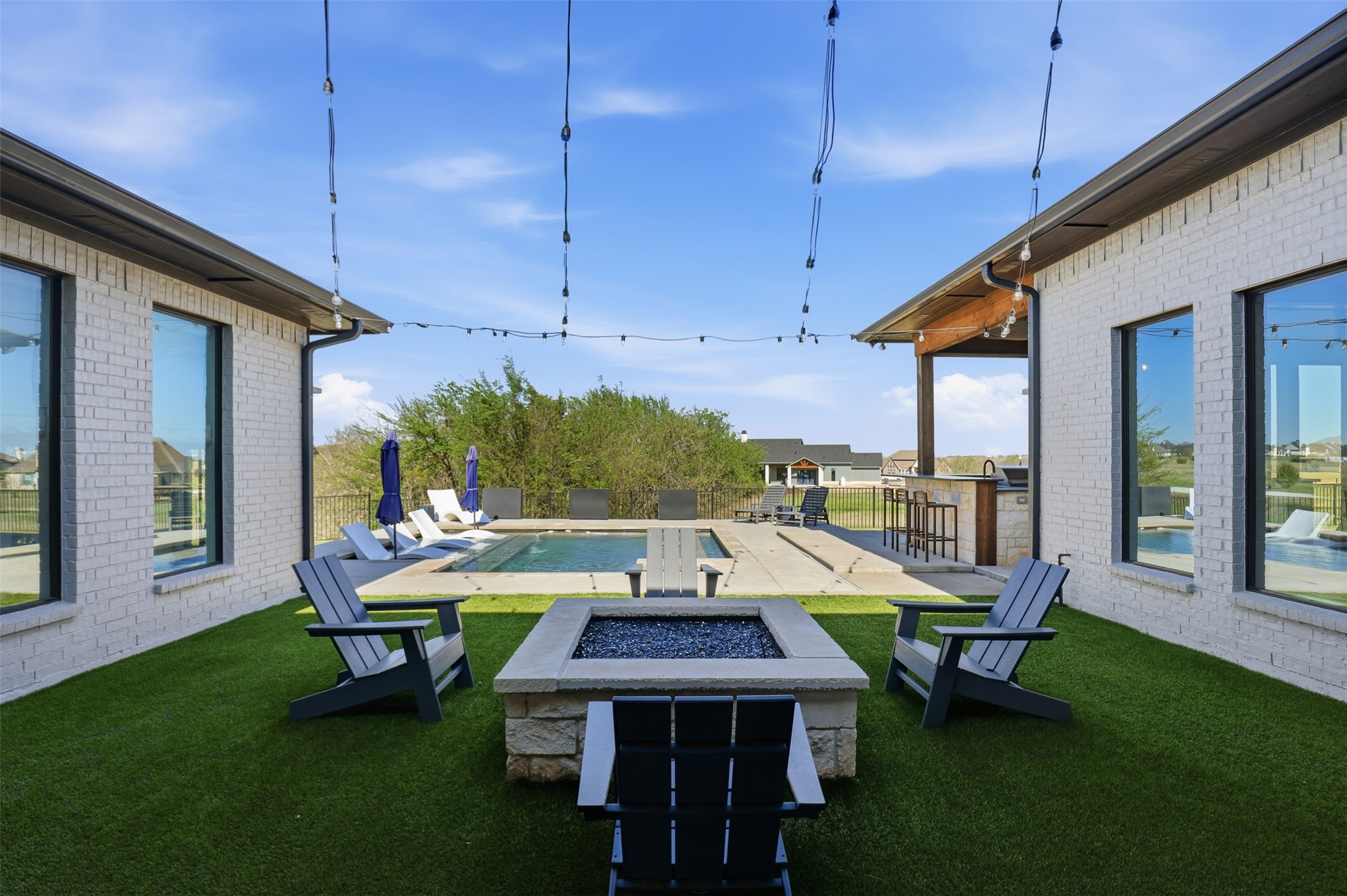 Backyard courtyard with a pool, stone fire pit, outdoor seating, and covered bar.
