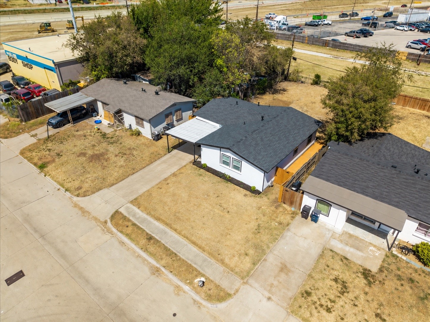 Aerial view of a white single-story house with a dark gray roof and dry front yard.