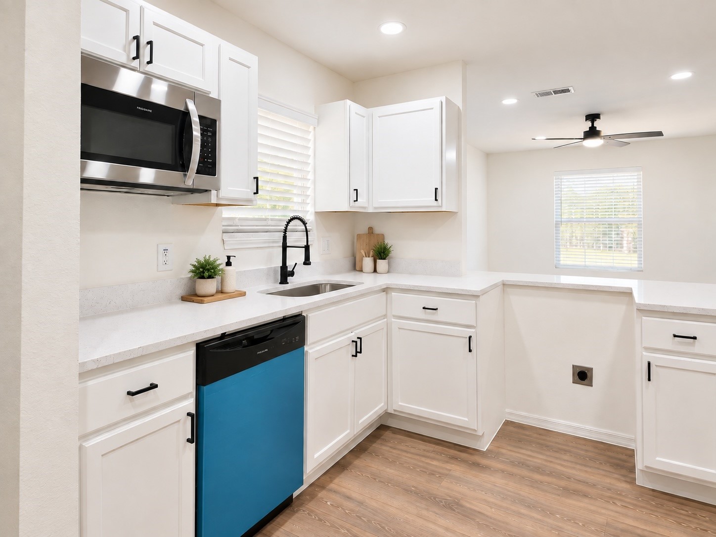 Kitchen with white cabinets and counters, black faucet, and a bright blue dishwasher.