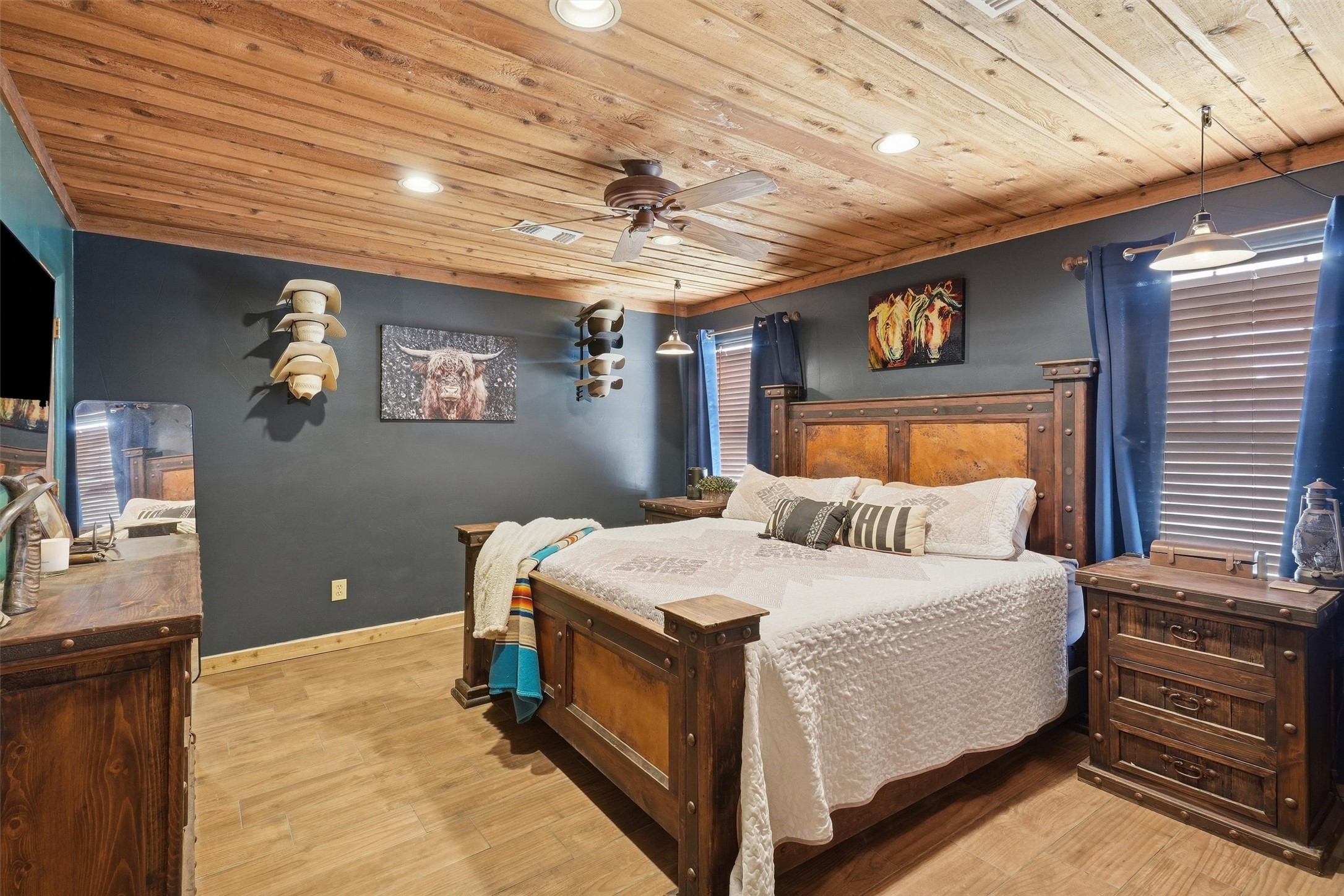 Furnished bedroom with a rustic wood bed, white bedding, and a warm plank ceiling with ceiling fan.