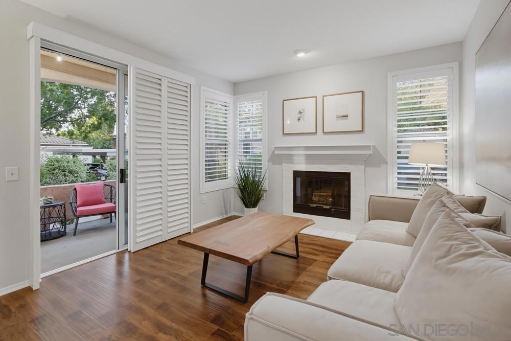 Living room with a fireplace, white sectional sofa, hardwood floors, and sliding glass doors to a patio.