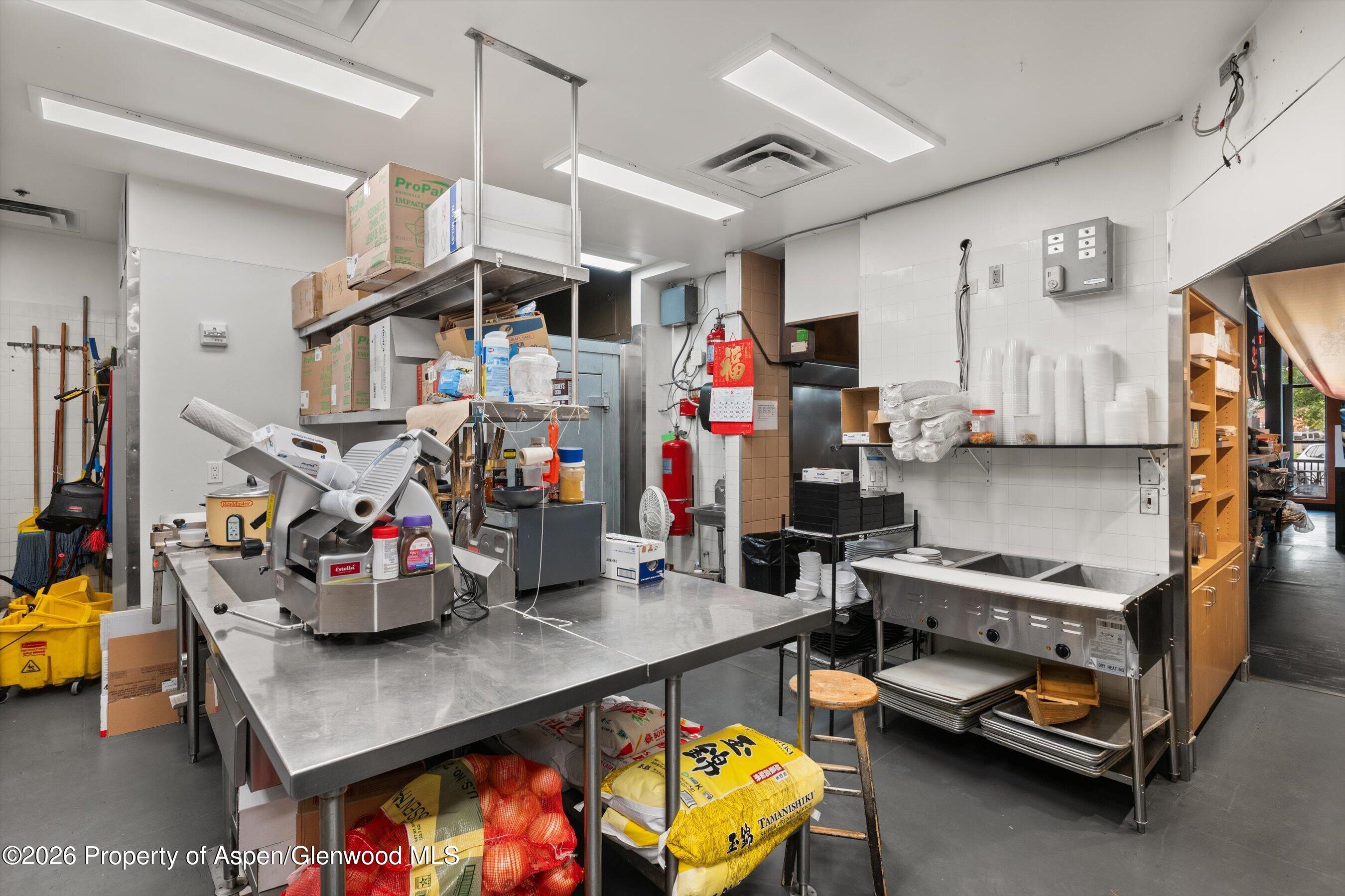 Commercial kitchen with stainless prep tables, a food slicer, and a multiwell steam table.