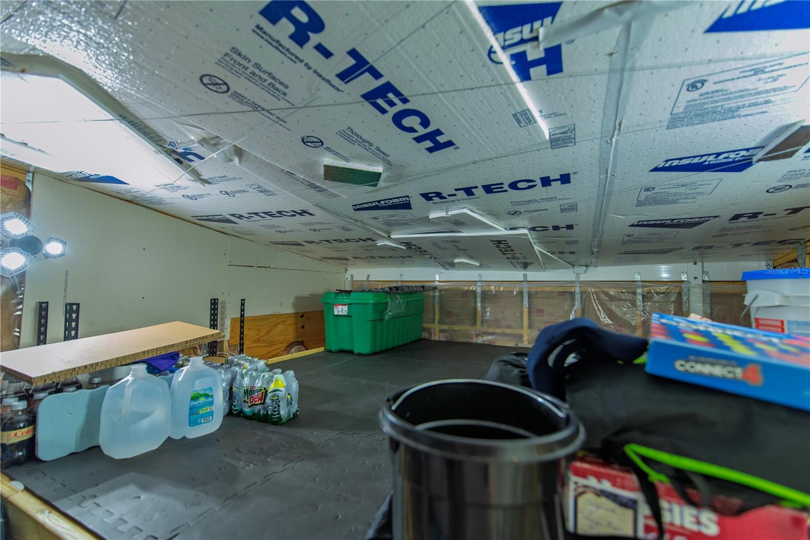 Garage with insulation panels across the ceiling and storage supplies on the floor.