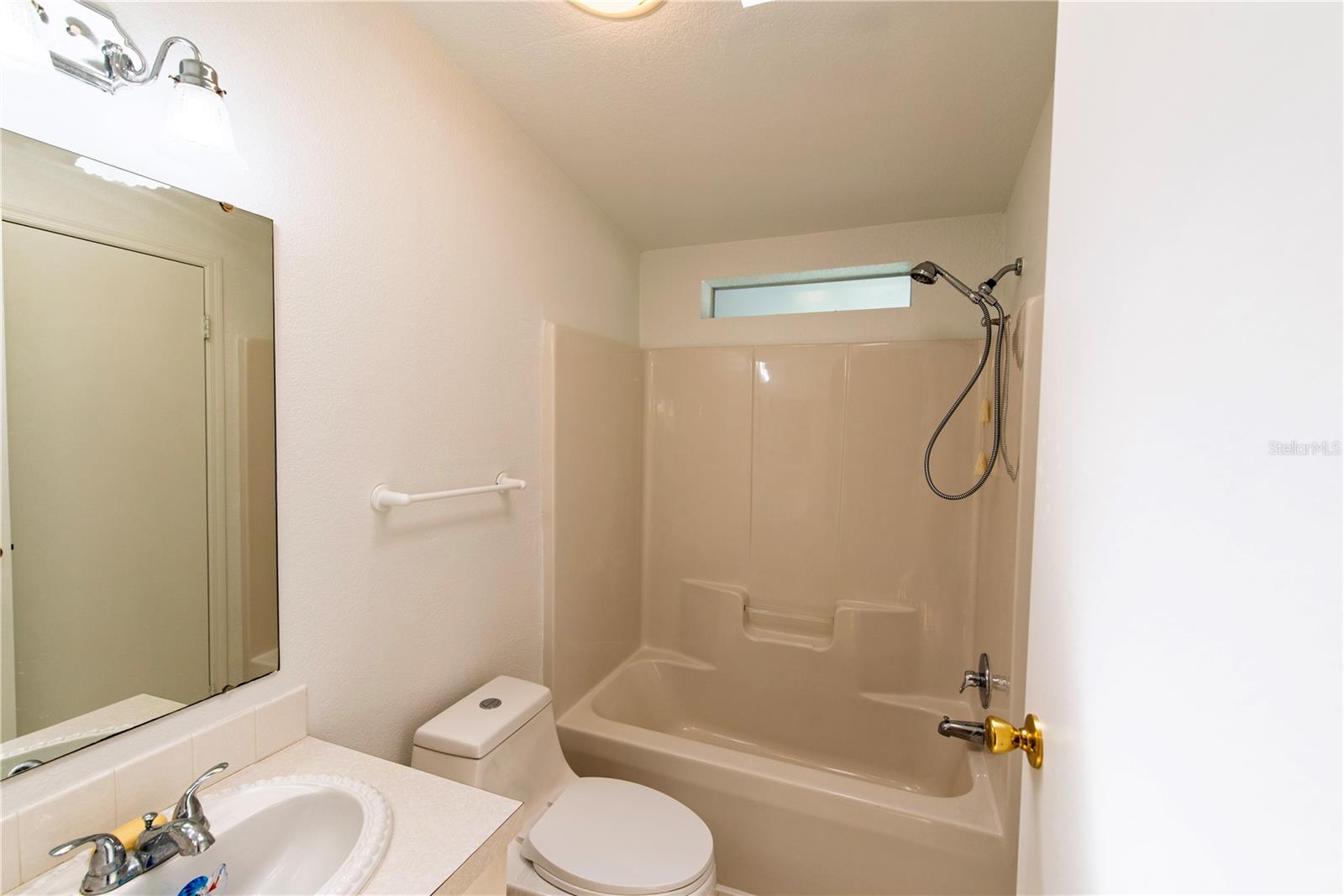 Bathroom with a beige tub and shower, toilet, and sink vanity.