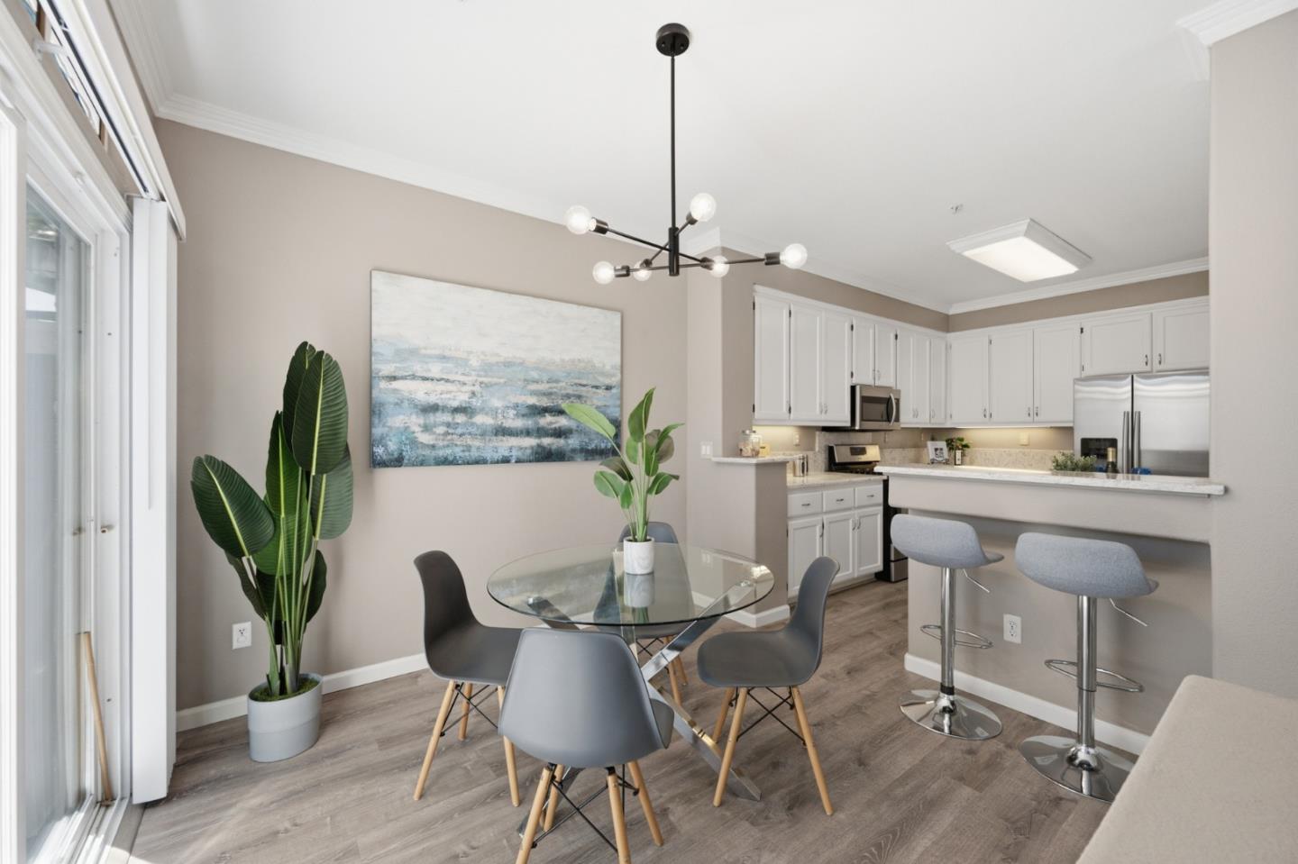 Open-plan dining area and kitchen with a glass table and breakfast bar stools.