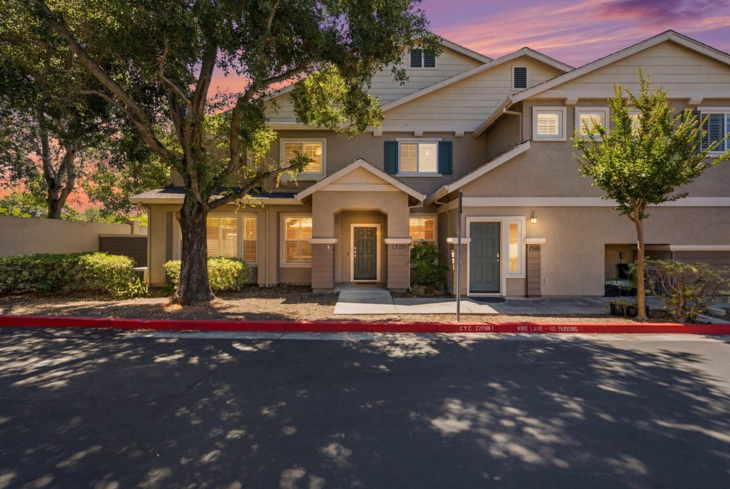 Attached two-story homes with gabled roofs and mature trees at dusk.