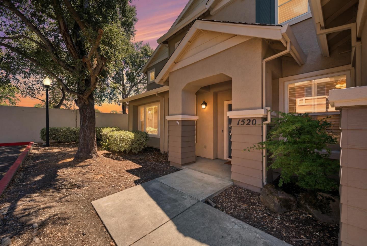 Home entrance marked 1520, with a covered porch and concrete walkway beneath a mature tree.