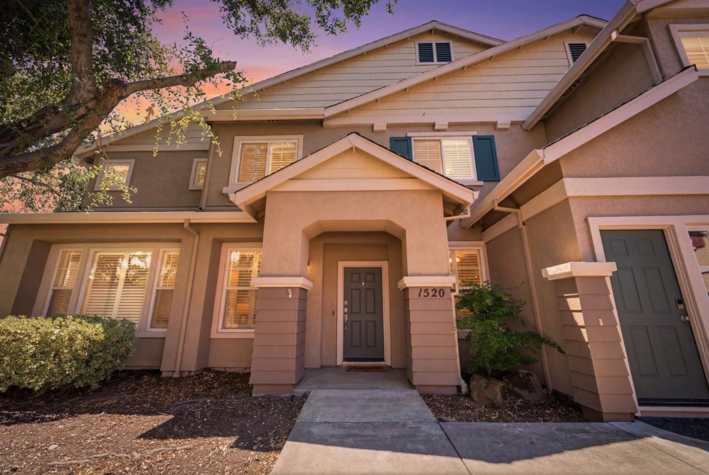 Two-story stucco home with a covered entrance and 1520 address plaque at dusk.