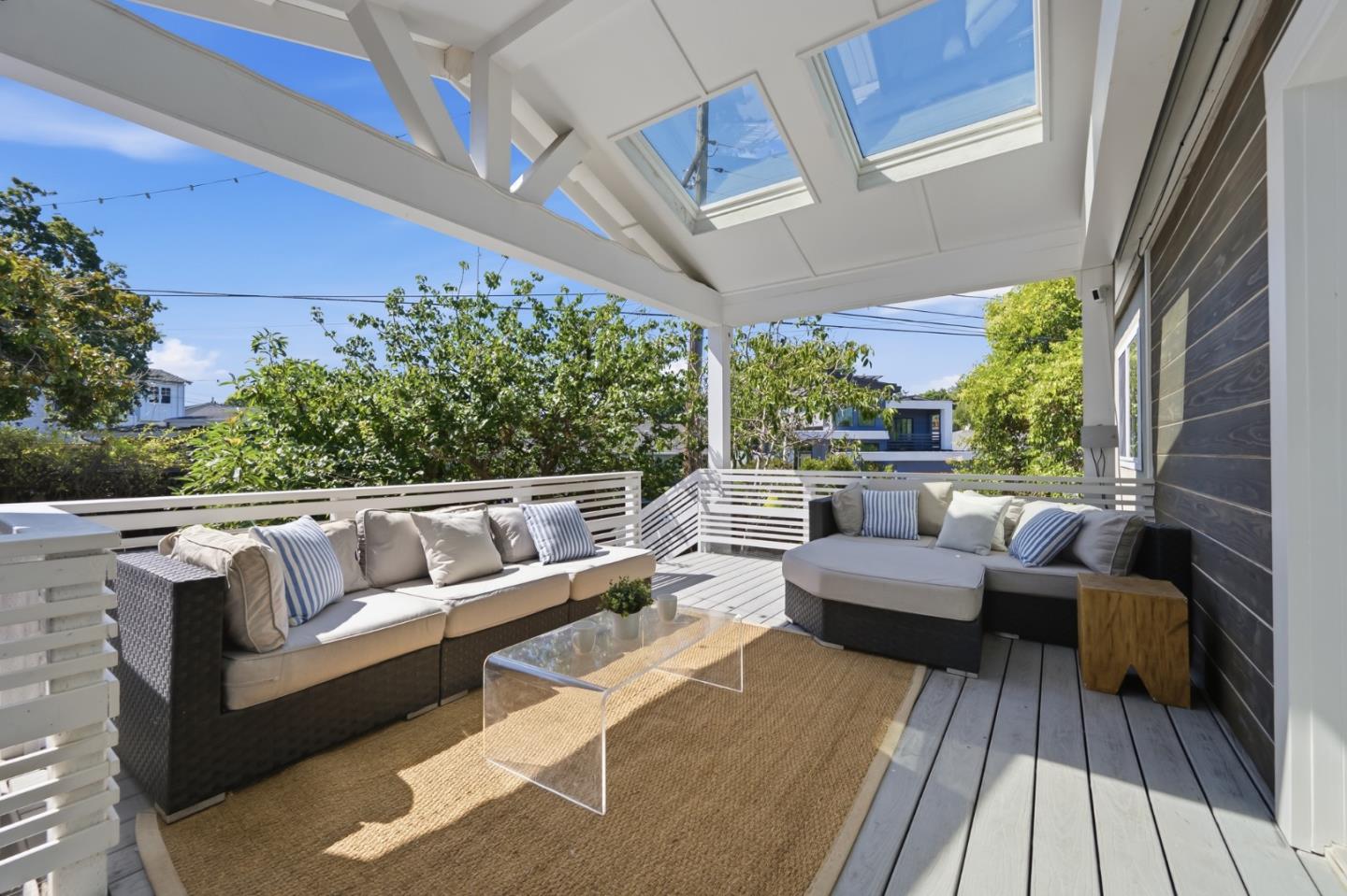 Covered deck with skylights, wicker seating, and a clear coffee table.
