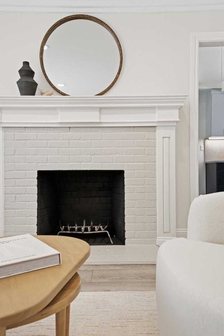 White brick living room fireplace with a round mirror above the mantel and neutral furnishings.
