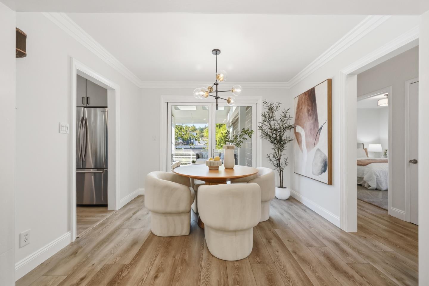 Dining room with a round table, cream chairs, and glass doors opening toward greenery.