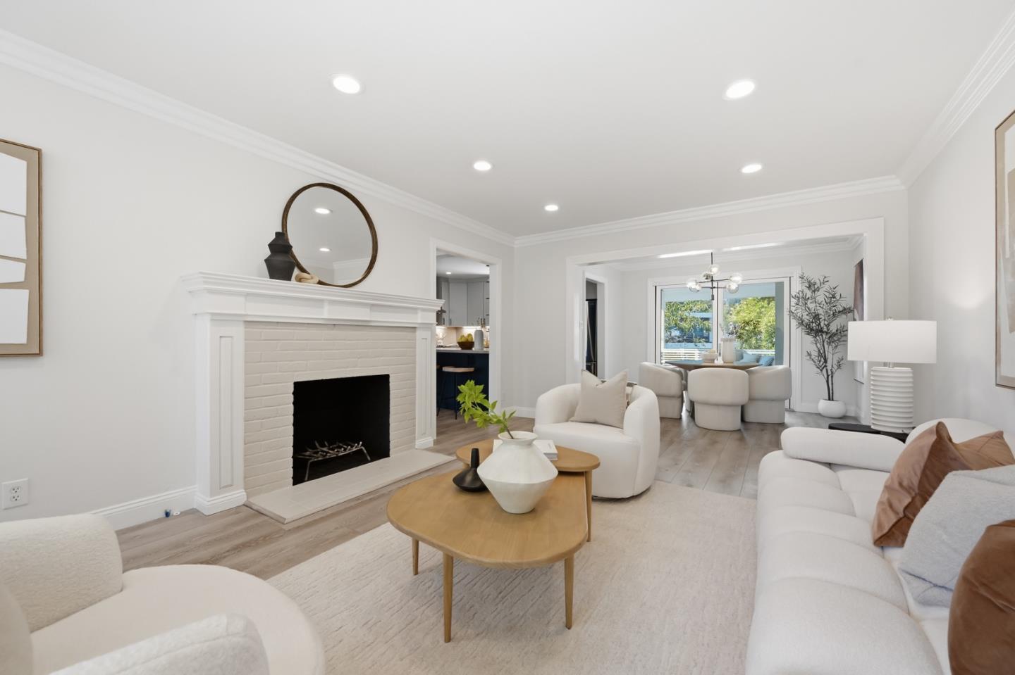 Staged living room with a white brick fireplace, white sofas, and an adjoining dining area.